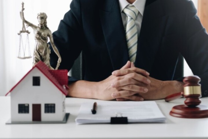 A property damage lawyer with a model house, gavel, and figure of Lady Justice