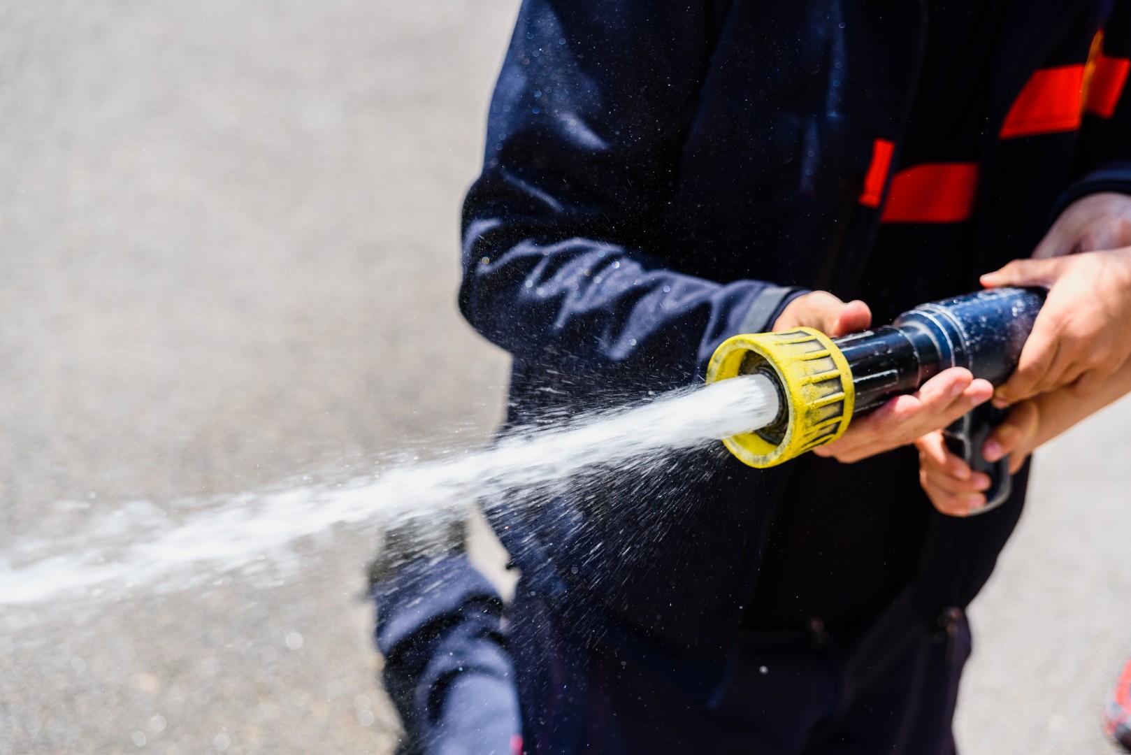 A firefighter holding an active fire hose